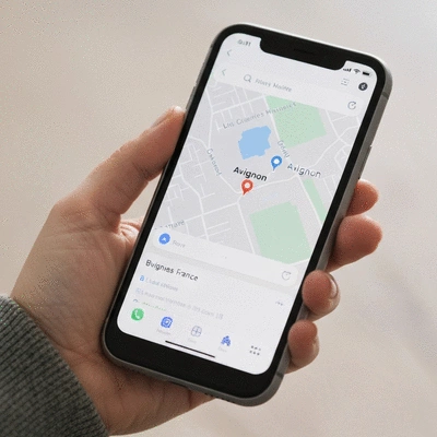 Close-up of a hand holding a smartphone, displaying a map application with a business pin in Avignon, France, no text, no words, no typography, no labels, clean image